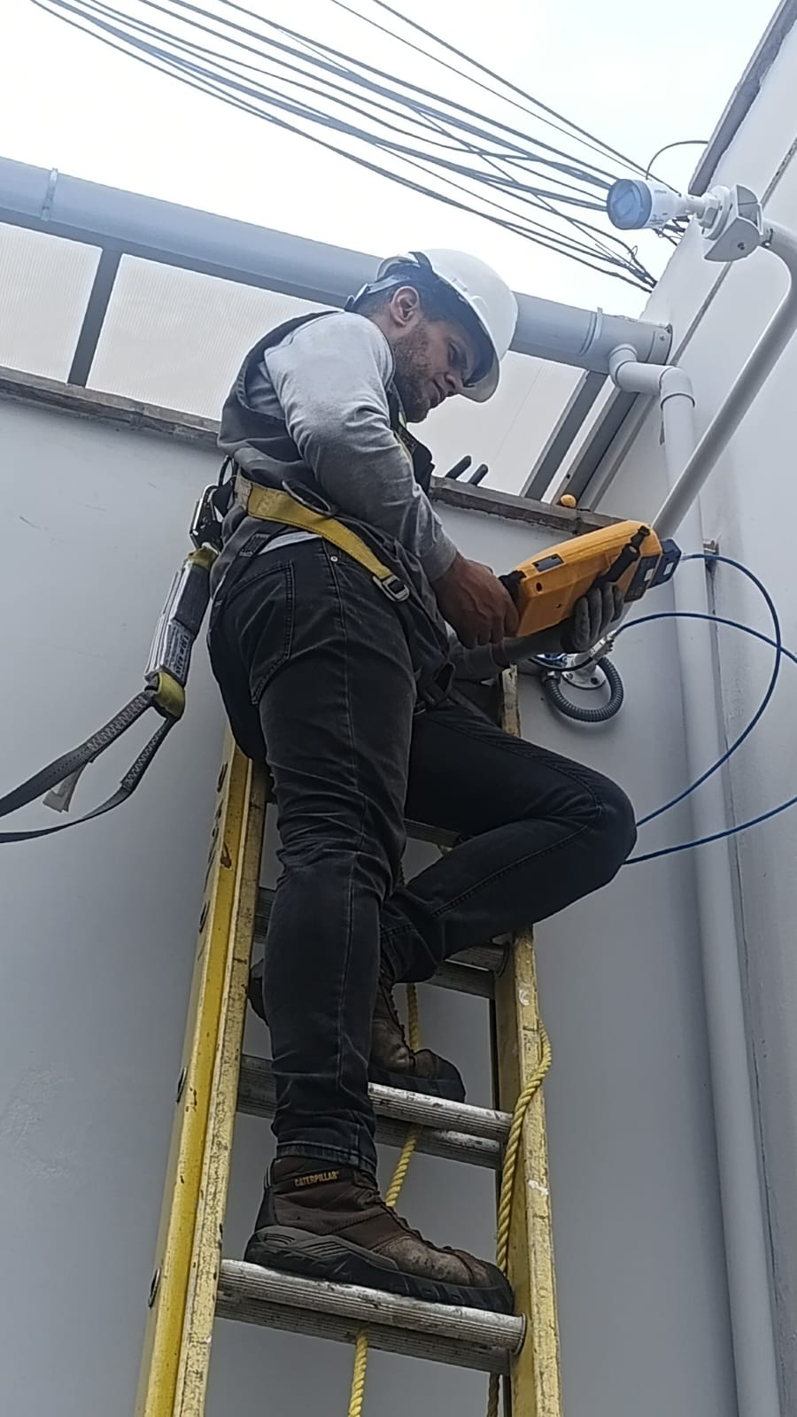 Técnico de JJService instalando cámara de seguridad en altura con equipo de protección